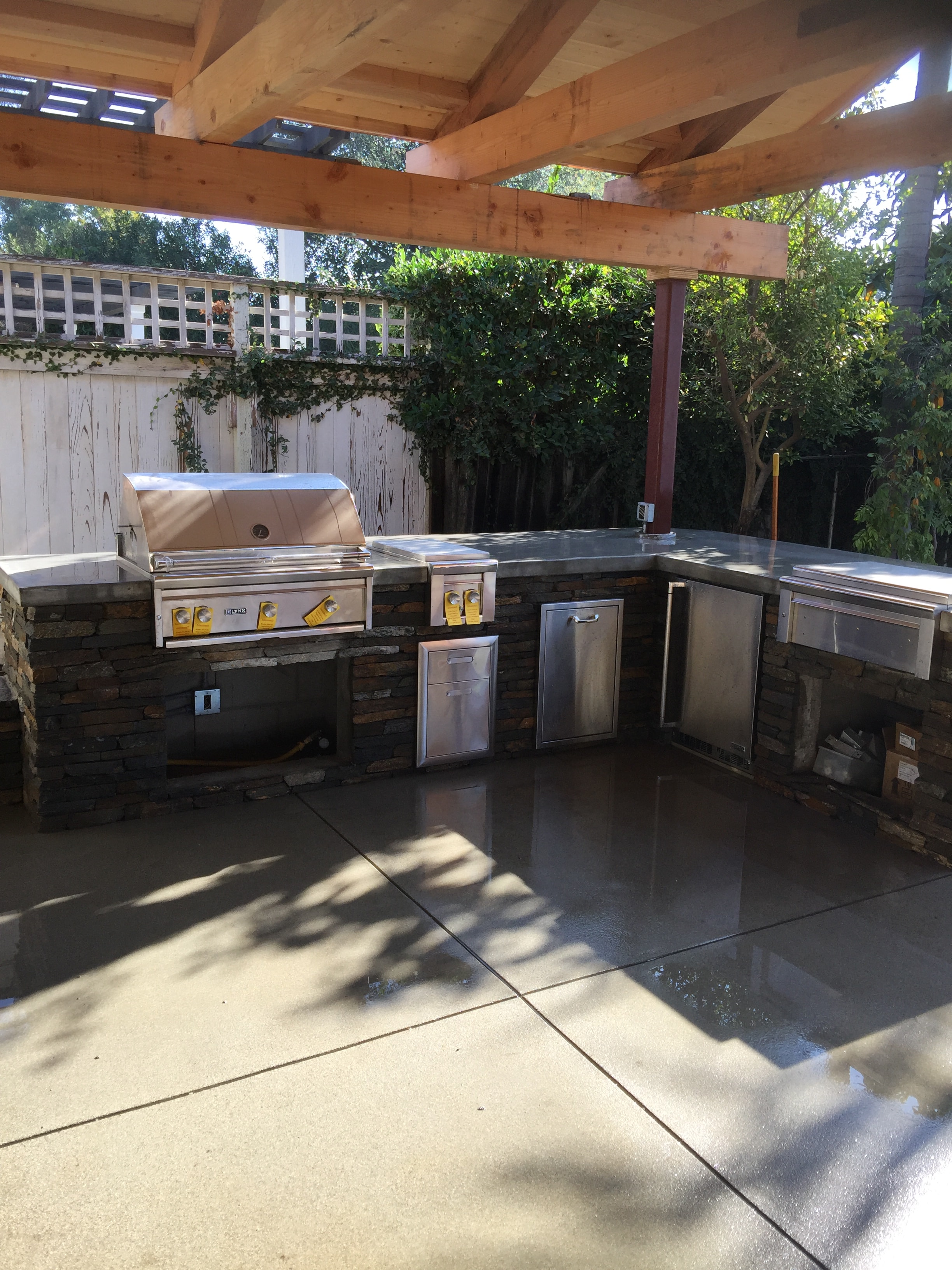 Outdoor kitchen with sand finish concrete patio and natural stone veneer in Pasadena, CA — Concrete Etc., Inc.