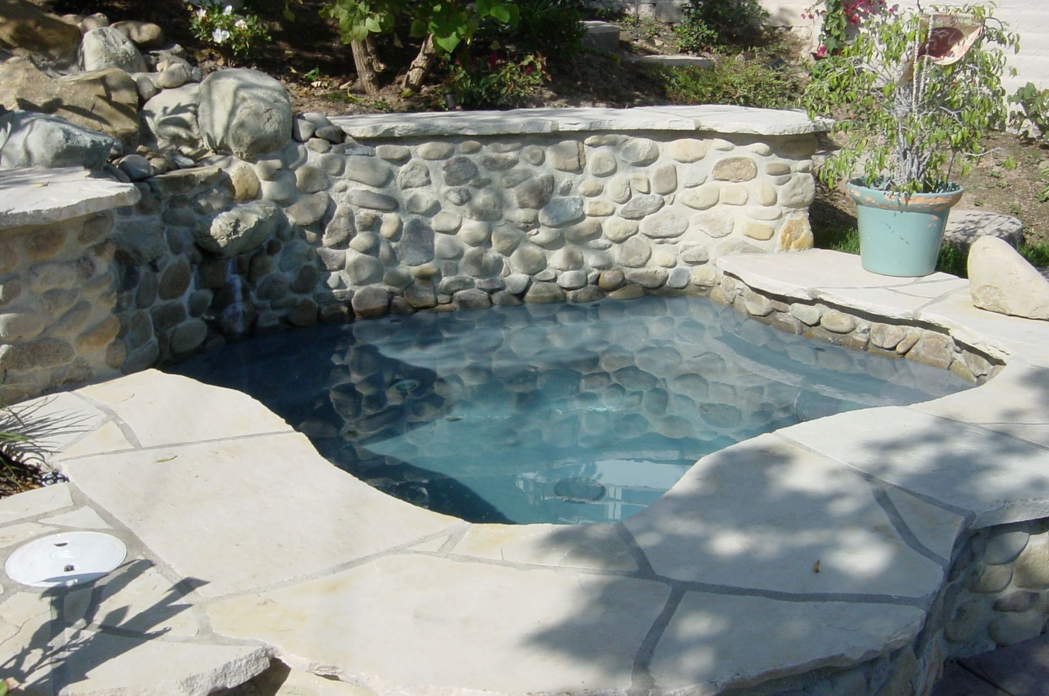 Natural flagstone concrete pool deck with river rock coping and stone waterfall feature in Los Angeles County by Concrete Etc., Inc.