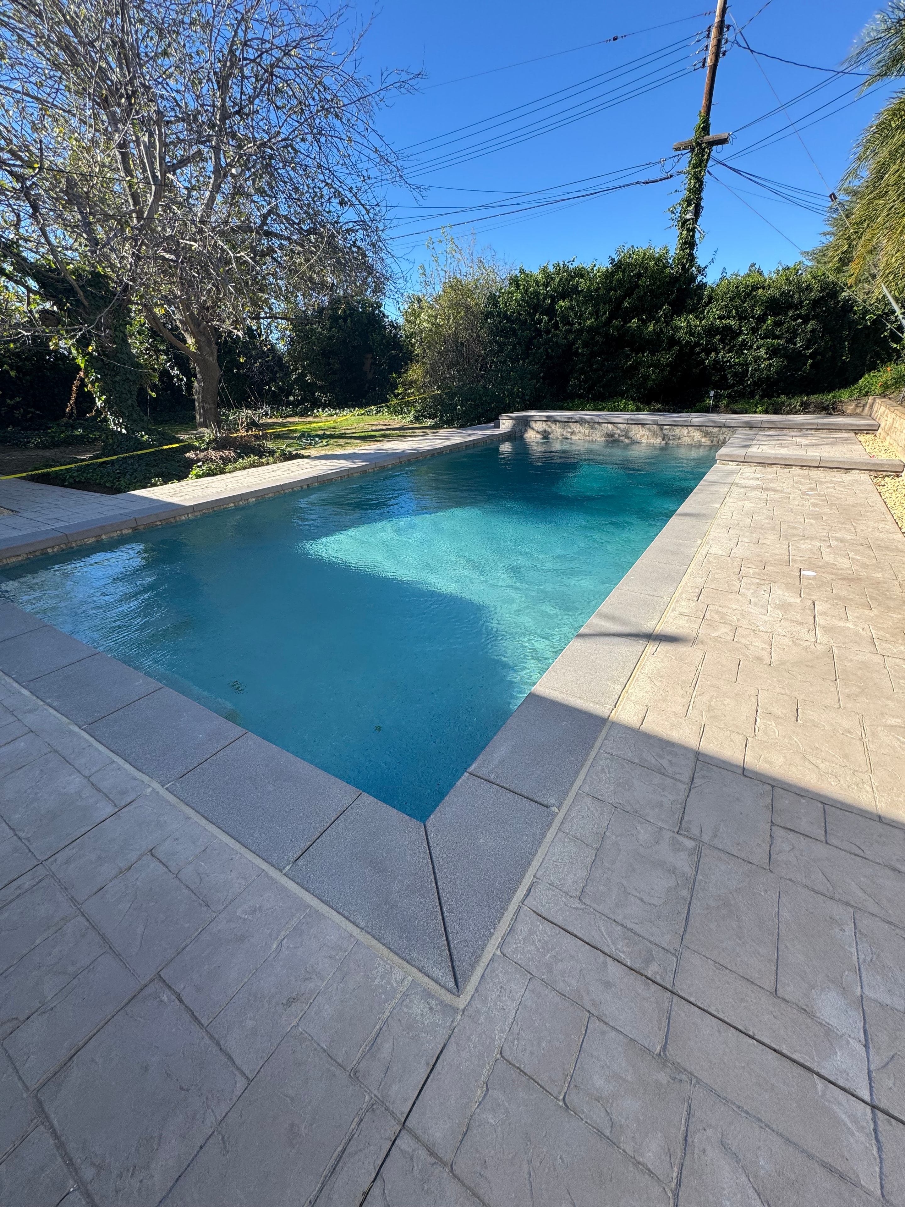 Stamped concrete pool deck with sand finish coping installed in San Fernando Valley, CA by Concrete Etc., Inc.