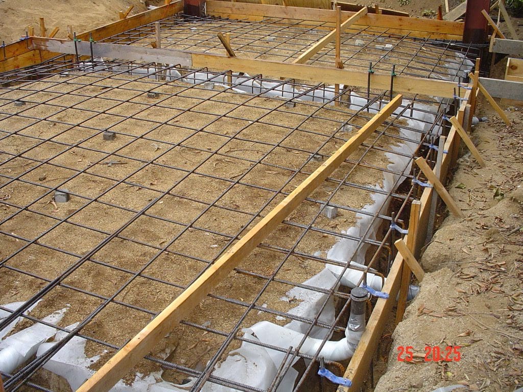 Concrete slab construction with rebar and piping.
